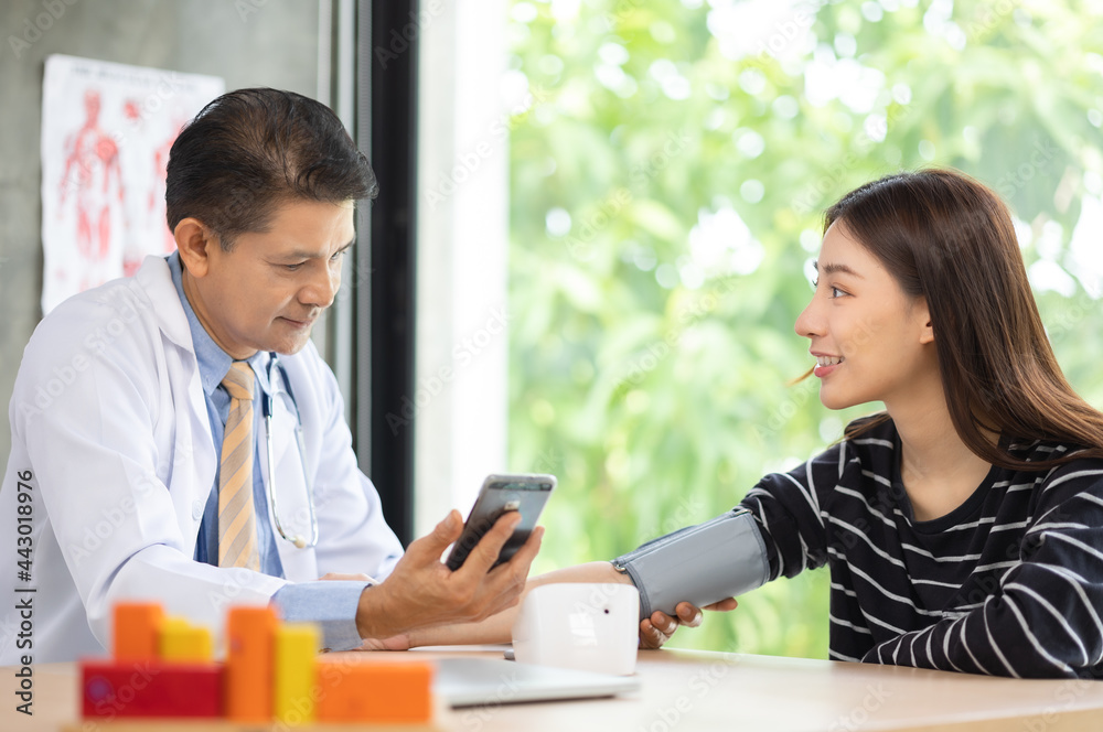 Senior doctor using sphygmomanometer with stethoscope checking blood pressure to a patient in the hospital. Senior doctor using sphygmomanometer with stethoscope checking blood pressure to a patient in the hospital.