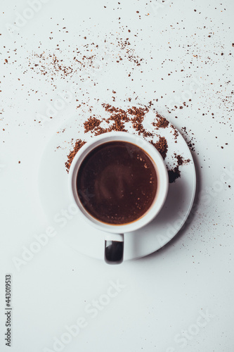 Taza de café con galletas y granos molidos en fondo blanco