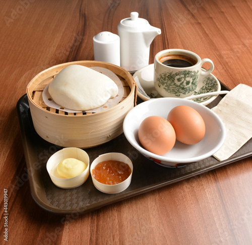 asian local traditional breakfast set halal menu with half boiled egg, baked roti mantou bun with butter and kaya jam and hot kopi coffee drink cuisine