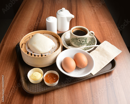 asian local traditional breakfast set halal menu with half boiled egg, baked roti mantou bun with butter and kaya jam and hot kopi coffee drink cuisine