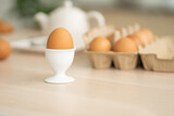 Selective focus at one boiled egg put on the kitchen desk with blurred eggs carton background of kitchen equipment ready to prepare food meal for breakfast. With copy space for add text