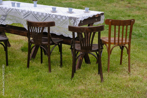 Wooden chairs at the tea table on the lawn before the rain. Selective focus. Vintage tea party scene. Ukraine. 