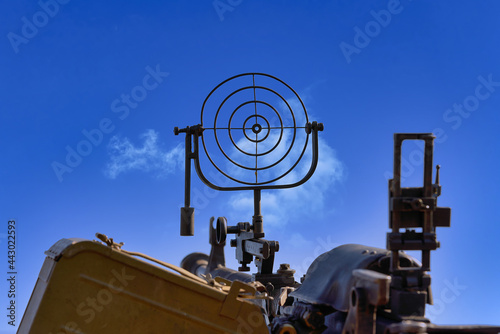 Obraz na plátně fragment of an anti aircraft machine gun, a round sight is aimed at clouds sky