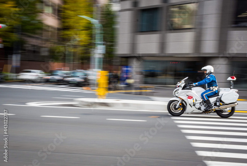Unidentified Japanese traffic police is riding the motorcycle on the road. The picture is panning to his motion.