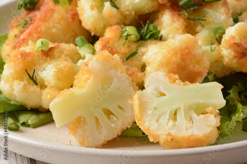 Fried cauliflower florets in batter on a white plate. Coated fried cauliflower