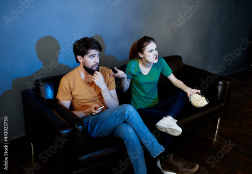 cheerful young couple at home watching TV evening relaxation at the root