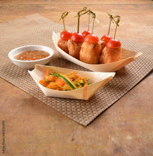 deep fried shrimp paste roll (wu Xiang) with achar and spicy sauce in bento box on wood table asian snack halal menu