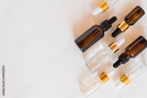 set of different dropper bottles with beauty care serum, hyaluronic acid and vitamins on wooden background. Home cosmetics and spa concept