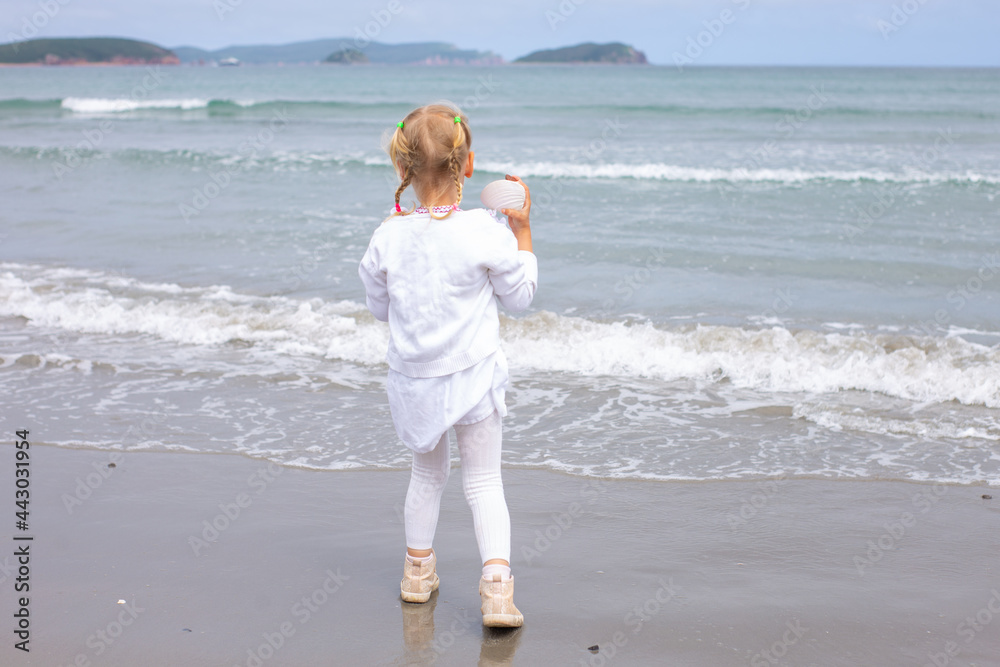 A little girl with pigtails standing next to a body of water in sunny day A little girl with pigtails standing next to a body of water in sunny day