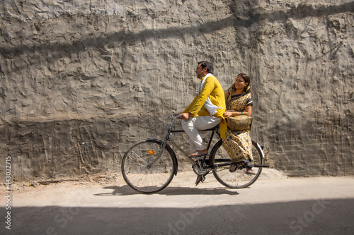 A HAPPY HUSBAND RIDING BICYCLE WITH WIFE SITTING BEHIND