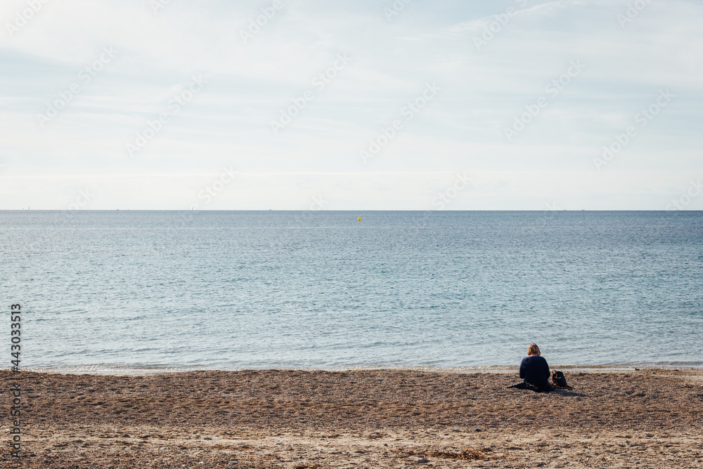 Une femme assise seule sur la plage. Une touriste seule à la mer regardant l'horizon. Une personne à la plage regardant la mer. Une femme assise seule sur la plage. Une touriste seule à la mer regardant l'horizon. Une personne à la plage regardant la mer.