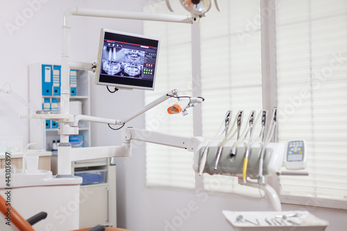 Dental instruments and tools in a dentist office. Stomatology cabinet with nobody in it and orange equipment for oral treatment.