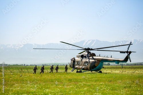 Fototapeta Naklejka Na Ścianę i Meble -  Military helicopter with soldiers. Armed conflict between Israel and Palestine, military action. A soldier in camouflage clothing goes to a military helicopter. Air armament, parachutist.