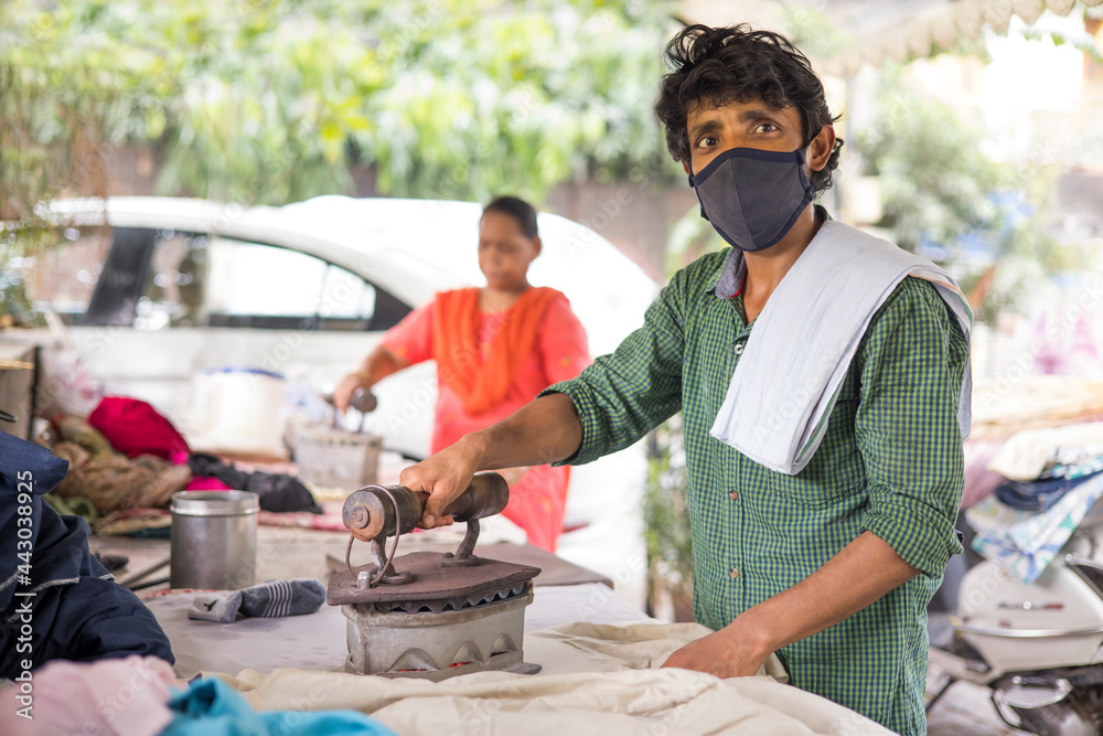 AN IRONER WEARING FACE MASK LOOKING AT CAMERA AN IRONER WEARING FACE MASK LOOKING AT CAMERA