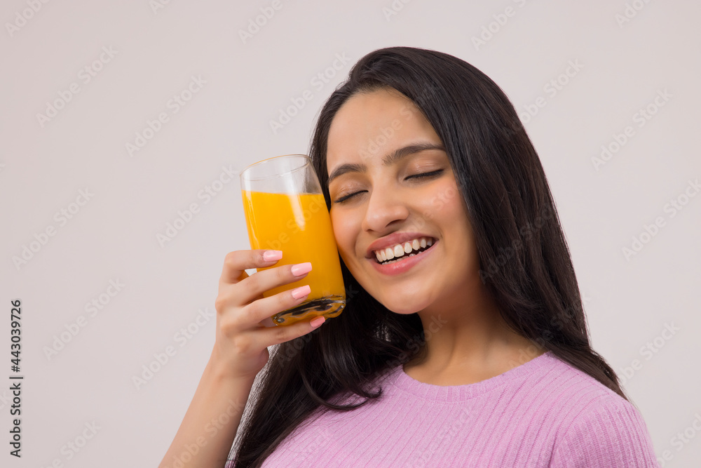 A HAPPY TEENAGER HOLDING A GLASS OF JUICE NEAR HER FACE A HAPPY TEENAGER HOLDING A GLASS OF JUICE NEAR HER FACE