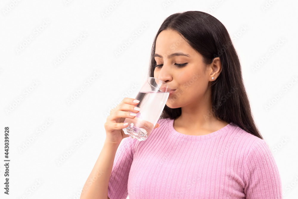 A TEENAGE GIRL DRINKING A GLASS OF WATER A TEENAGE GIRL DRINKING A GLASS OF WATER