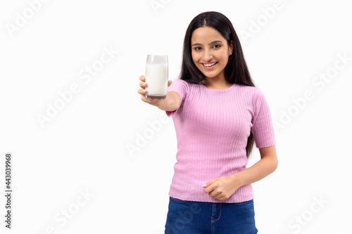 A TEENAGE GIRL HAPPILY SHOWING A GLASS OF MILK IN FRONT OF CAMERA