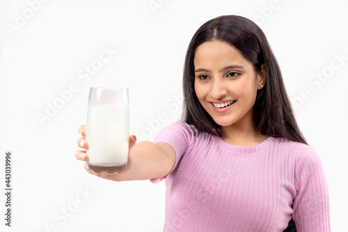 A TEENAGE GIRL HAPPILY LOOKING AT A GALSS OF MILK IN HAND