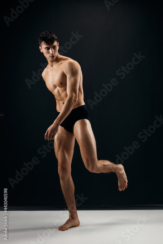 male bodybuilder with naked body in black panties in the studio