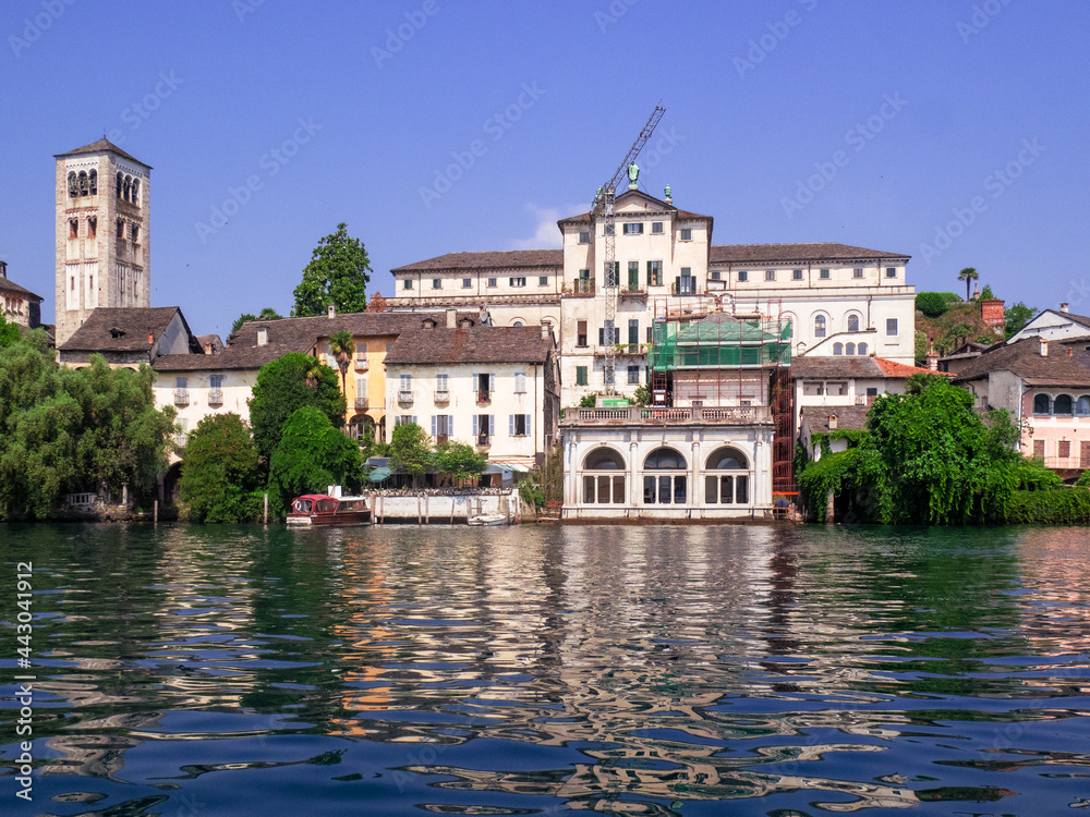 Stunning San Giulio island in the middle of Orta lake, view of the elegant villas and the monastery from the boat. Piedmont, italian lakes, Italy.