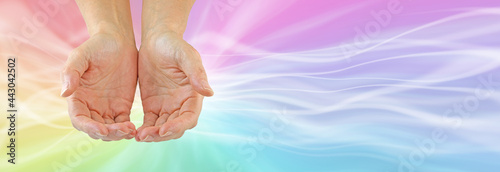 Sending out multicoloured healing energy message banner - female cupped hands against a rainbow coloured flowing background with copy space for messages 
 photo