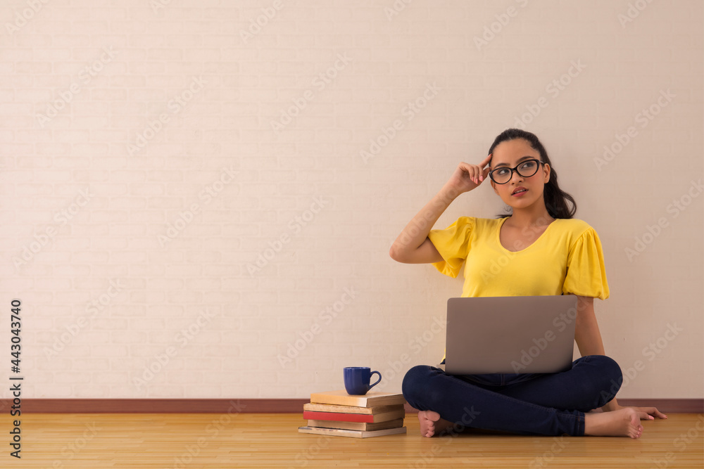 A young woman musing while working on her laptop. A young woman musing while working on her laptop.