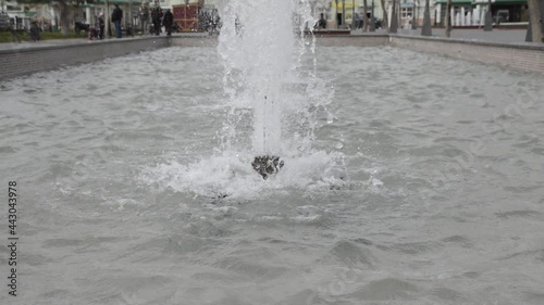 Wallpaper Mural a small fountain in a city park throws up thick jets of water, in the background there are blurry figures of people walking Torontodigital.ca