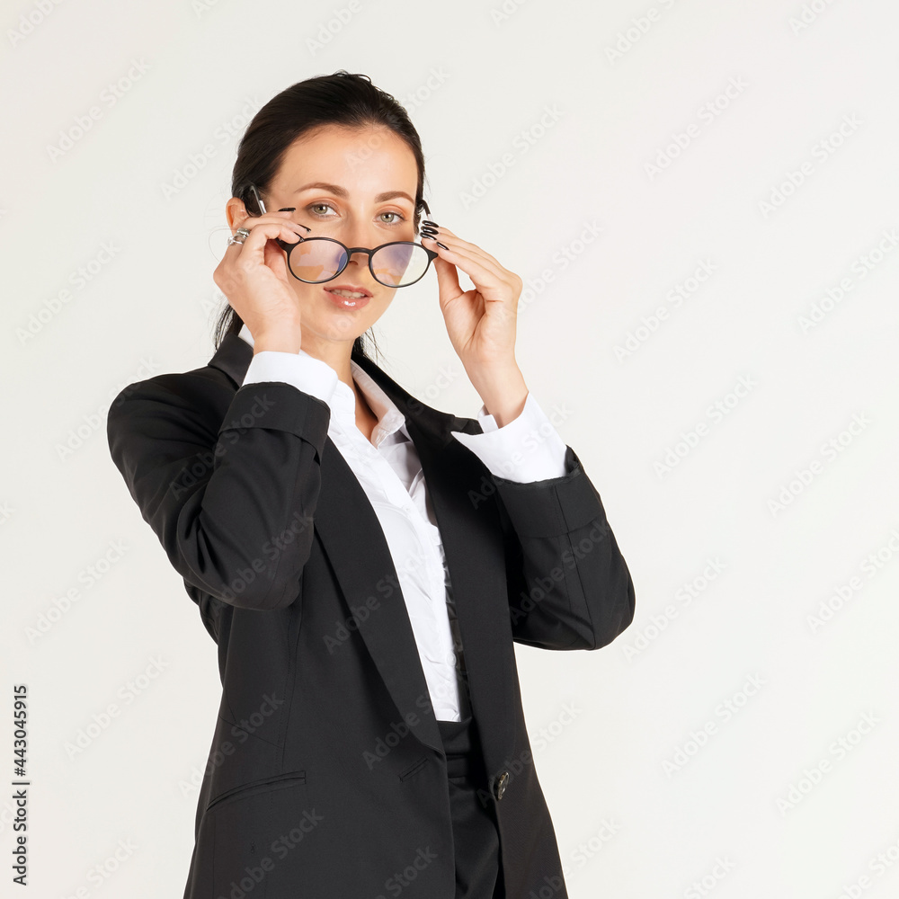 Business women in black suits hold eyeglasses with both hands While looking ahead. Portrait on white background with studio light. Business women in black suits hold eyeglasses with both hands While looking ahead. Portrait on white background with studio light.