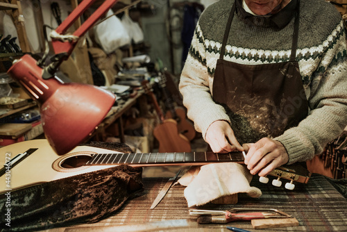 Crop artisan repairing guitar fret at workshop