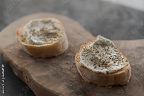 Ciabatta slices with cream cheese and herbs on olive wood board