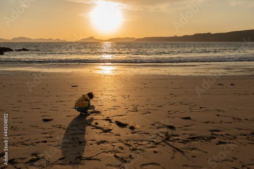 child playing on the beach in the sand during the beautiful winter sunset
