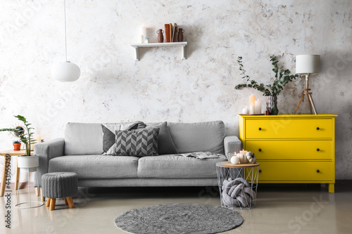 Trendy interior of living room with grey sofa and yellow commode