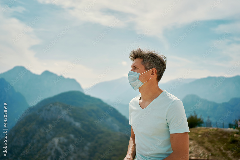 Naklejka premium Tourist man wearing face mask enjoying amazing mountains view, traveling vacation to Turkey during coronavirus epidemic