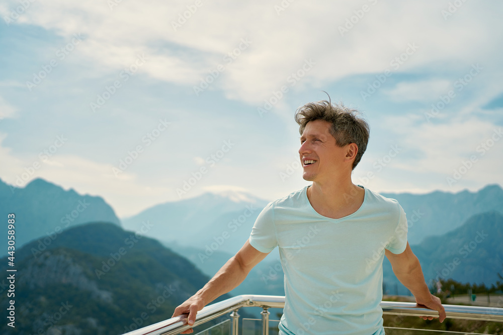 Positive happy man tourist enjoying fresh air at viewpoint among mountains and cloudy sky. travel to the mountains region of Turkey
