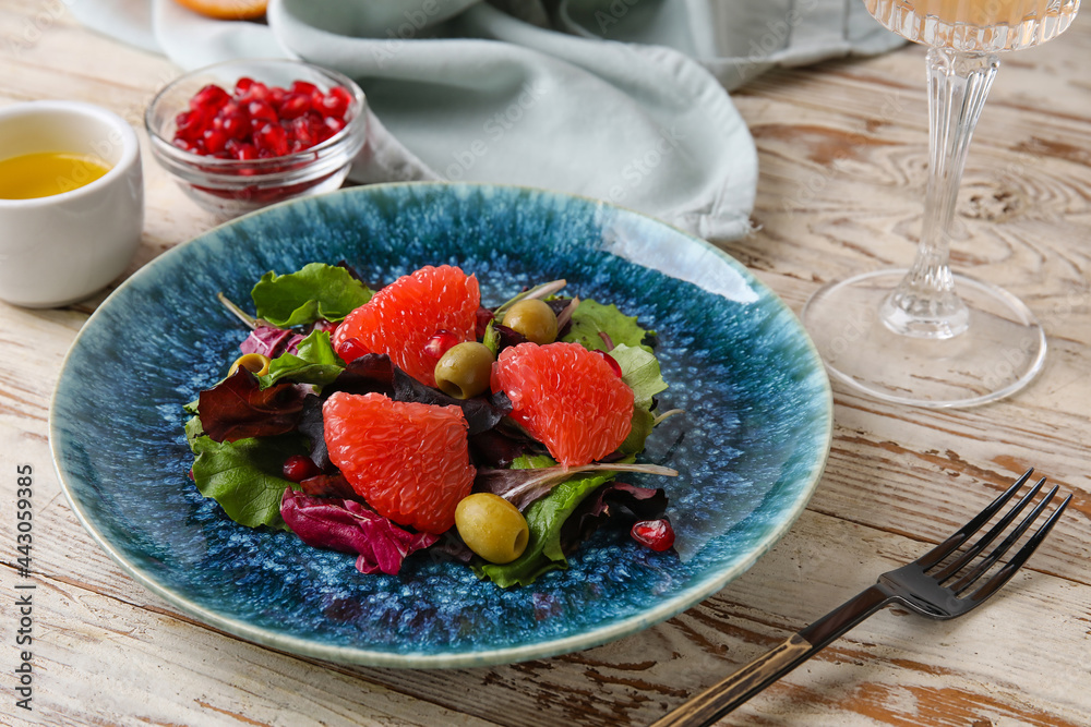 Plate with tasty grapefruit salad and glass of lemonade on light wooden table Plate with tasty grapefruit salad and glass of lemonade on light wooden table