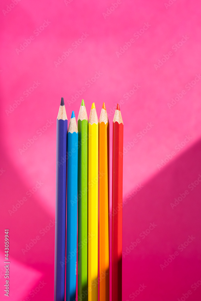 LGBT gay pride flag made of rainbow colored pencils. Creative, stationery still life on bright pink background with interesting shadows, copy space. LGBT gay pride flag made of rainbow colored pencils. Creative, stationery still life on bright pink background with interesting shadows, copy space.