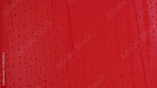 Video of rain and water droplets flowing through the red wall and the sound of rain.