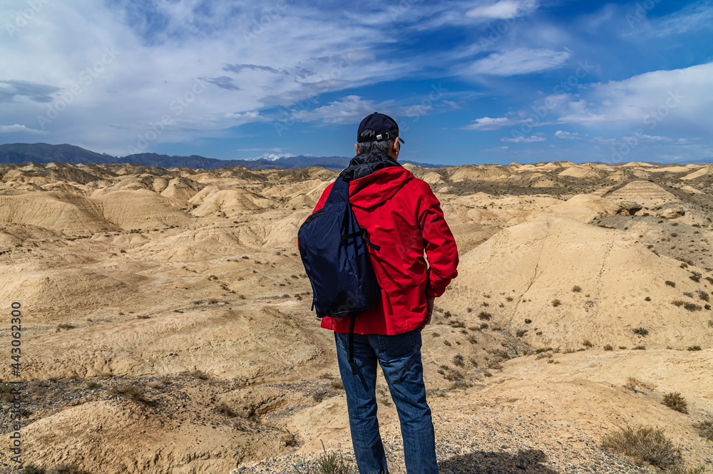 Man with a backpack looks at the sand dunes