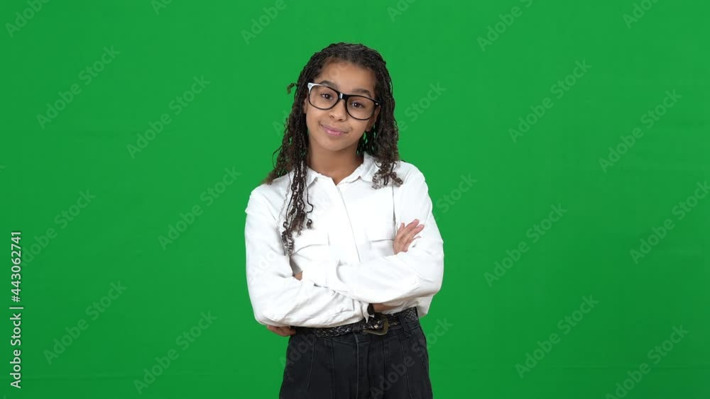 Front view of adolescent African American teen nerd girl shaking finger gesturing on green screen and adjusting eyeglasses. Portrait of smart intelligent teenage student posing at chromakey background Front view of adolescent African American teen nerd girl shaking finger gesturing on green screen and adjusting eyeglasses. Portrait of smart intelligent teenage student posing at chromakey background