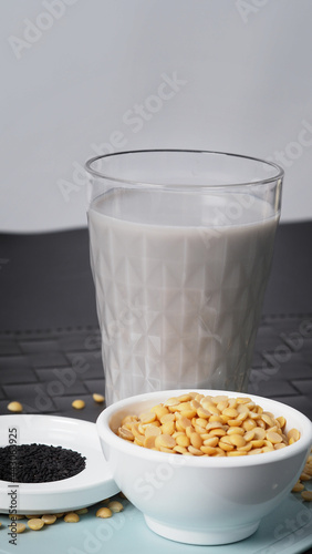 Soy milk blended with black sesame in clear glass on black plate mat. Black sesame seed and soy beans in a cup. Black sesame soy bean blended milk. Healthy drink with natural ingrediant. Soya milk.