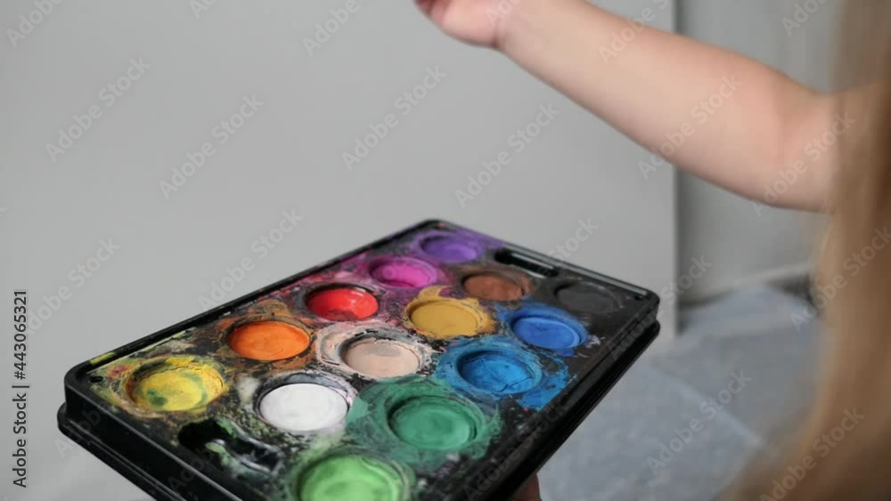 kid hand picks up colorful paint with a brush kid hand picks up colorful paint with a brush