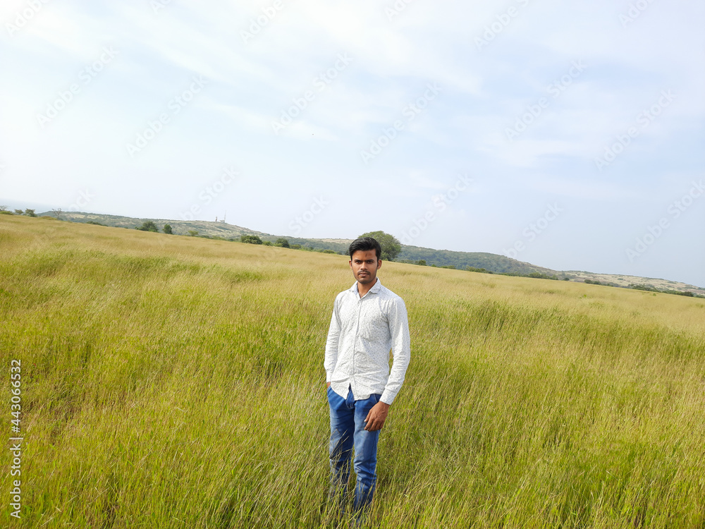 Indian young man, person on a meadow, young man in the wild, people in field. 