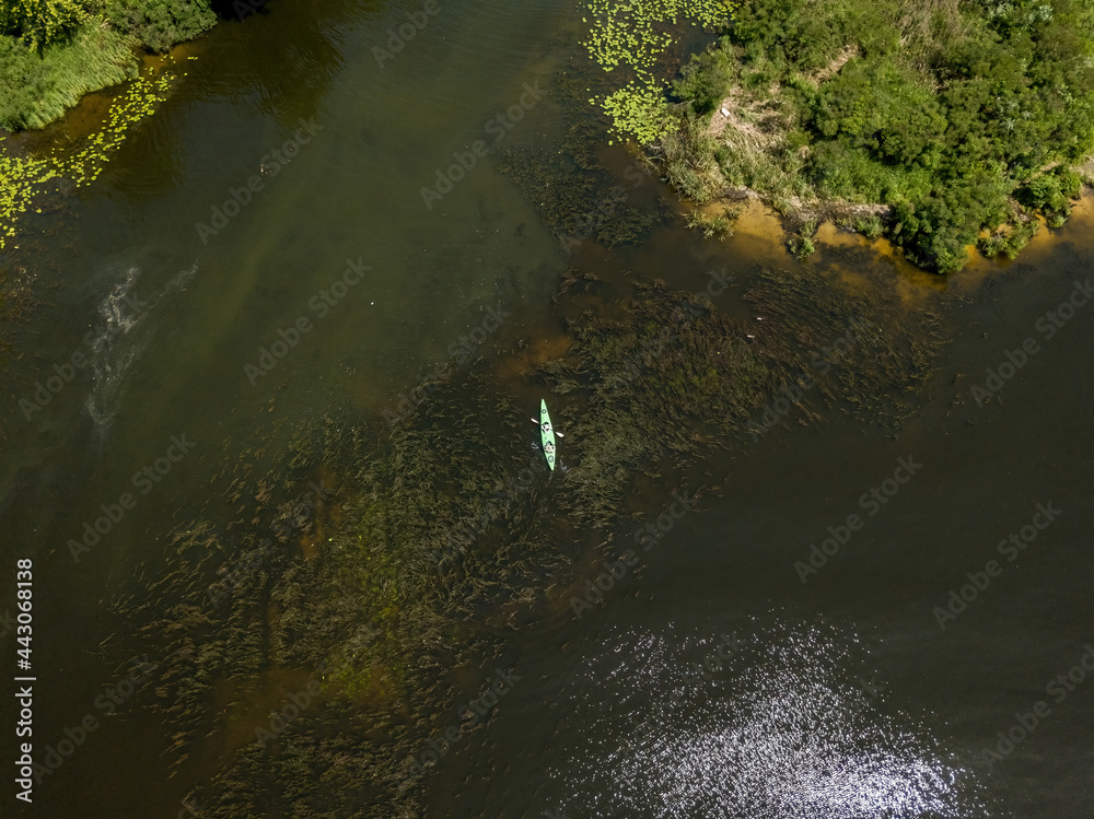 Kayak on a narrow river with green banks in summer. Aerial drone view.