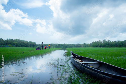 Asian fish hunters are fishing under a cloudy blue sky. Beautiful landscape photography river and green grass in Kerala, India.