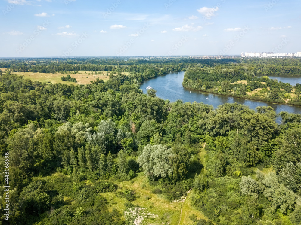 Green meadow near the river in summer. Aerial drone view.