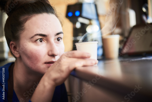 Female barista inspecting a perfect coffee in a paper cup