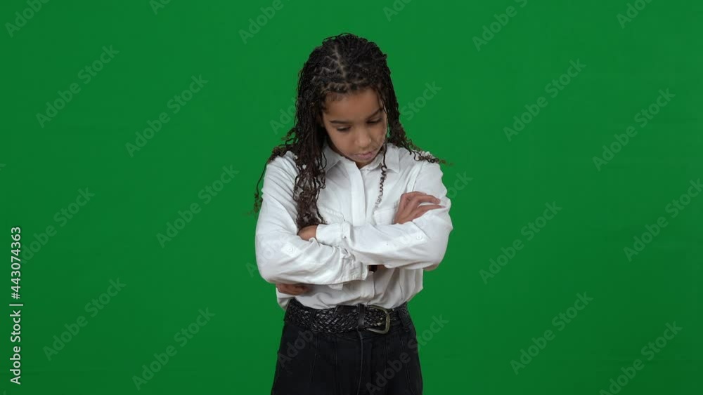 Portrait of teen African American girl looking around crossing hands and looking at camera with sad facial expression. Adolescent teenager posing at chromakey green screen. Sadness and despair Portrait of teen African American girl looking around crossing hands and looking at camera with sad facial expression. Adolescent teenager posing at chromakey green screen. Sadness and despair