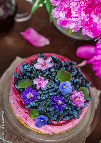 Purple cheesecake with honeysuckle  violet flowers and a background of peonies and a whole cake