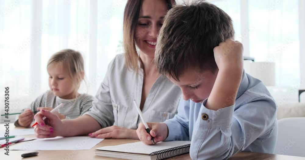 Mother helping daughter and son doing homework at home Mother helping daughter and son doing homework at home