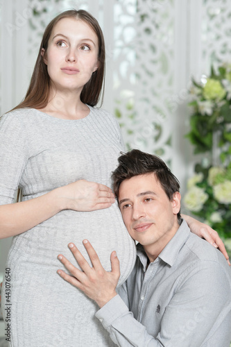 happy pregnant woman with husband at home. Man with head on belly of wife